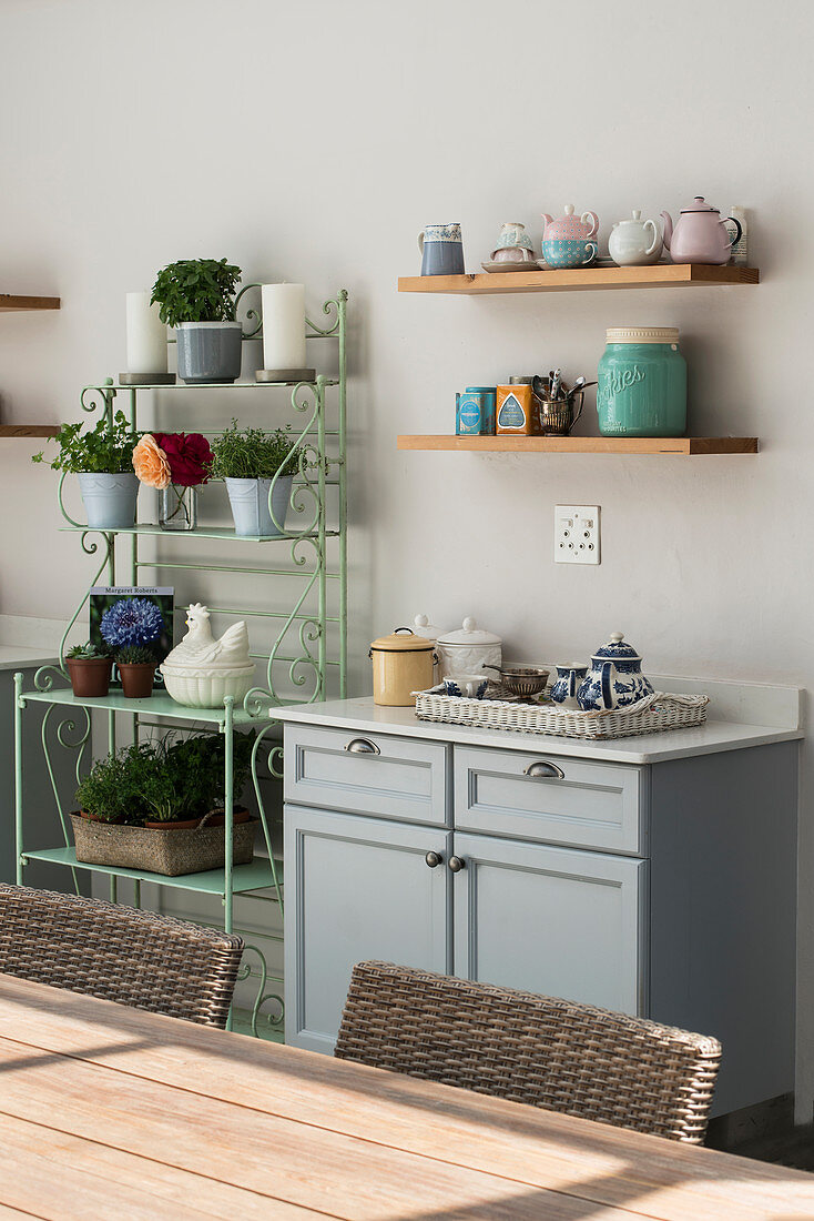 Küchenunterschrank, Regalbretter mit Geschirr und Metallregal mit Zimmerpflanzen