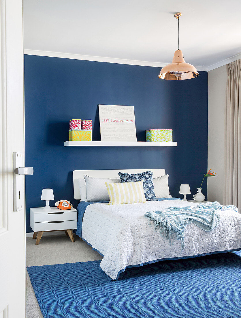 Double bed in bedroom with blue wall and blue rug