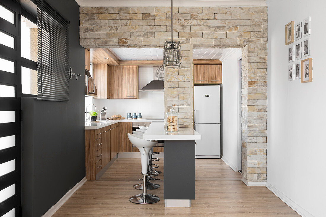 Stone wall with two openings leading into open-plan kitchen