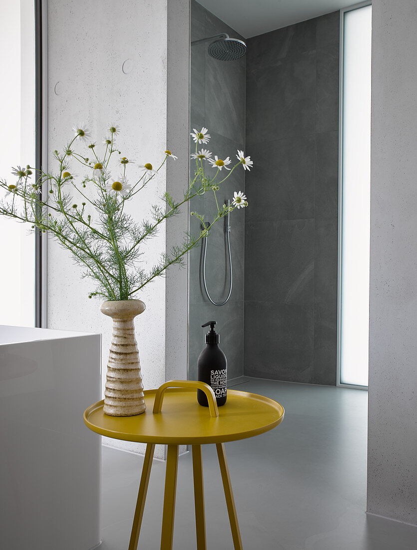 Blumen in der Vase auf gelbem Beistelltisch im modernen Bad