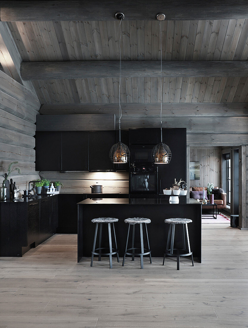 Black kitchen in log cabin with exposed roof structure