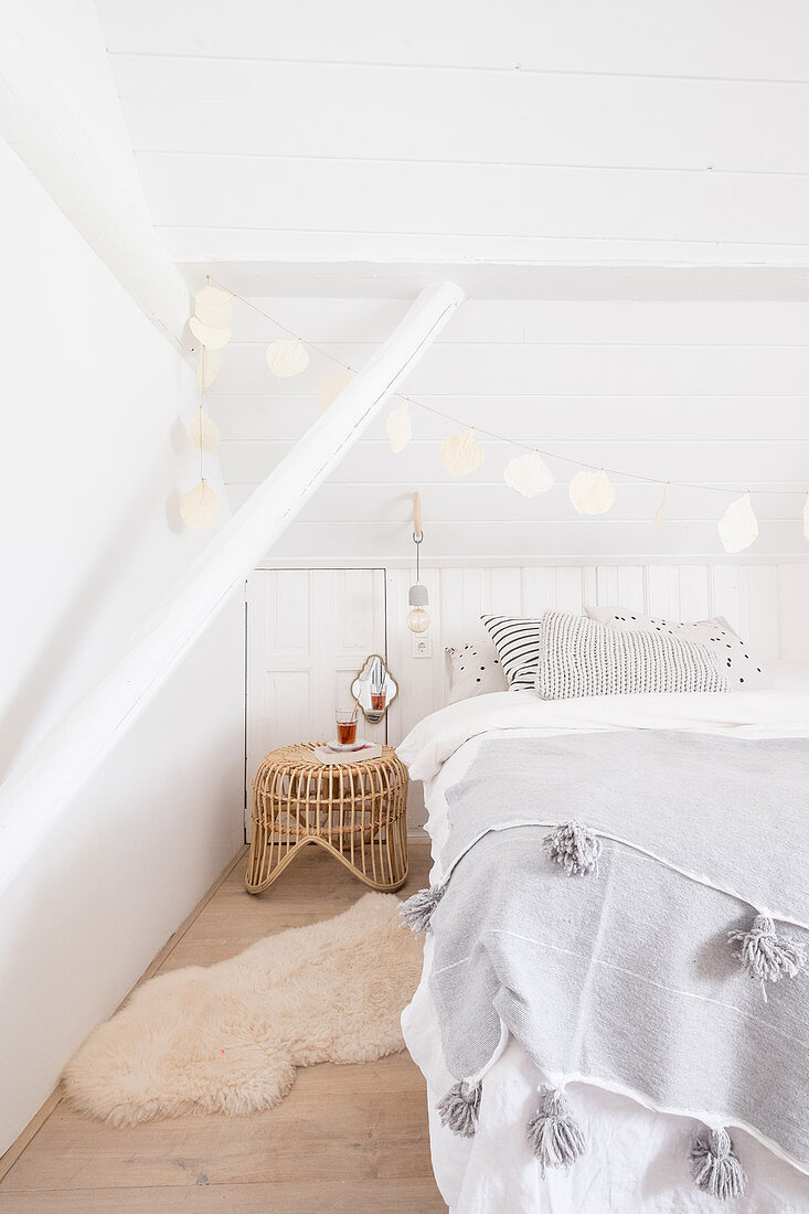 Weißes Schlafzimmer mit Doppelbett, DIY-Girlande aus weiß besprühten Blättern