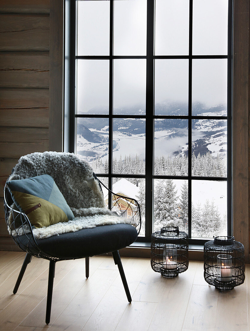 Sessel vorm bodentiefen Fenster mit Blick auf die Winterlandschaft
