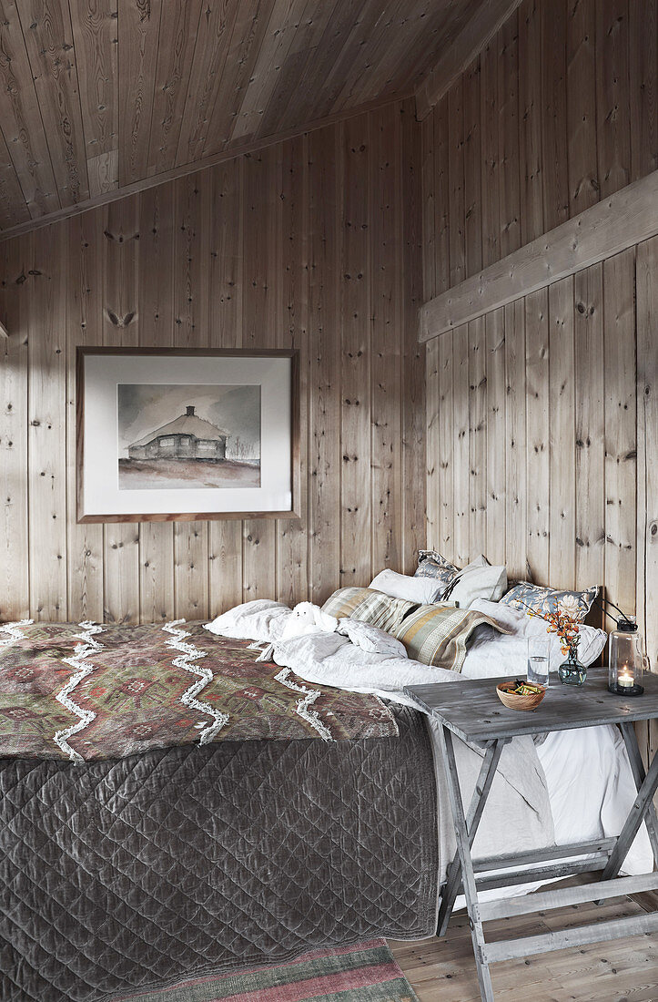 Gemütliches Schlafzimmer mit Doppelbett und Holzverkleidung