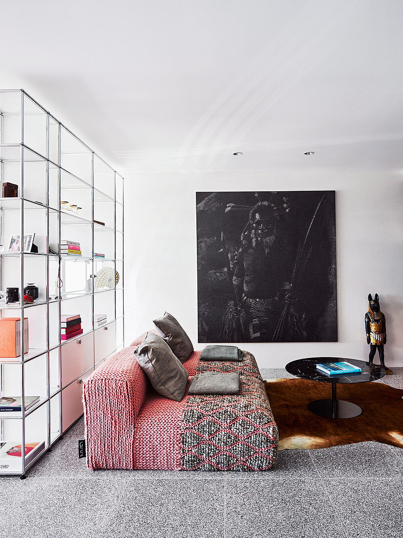 Rotes Designersofa, Coffeetable und Bild vor Raumhohes, transparentes Regal in offenem Wohnraum