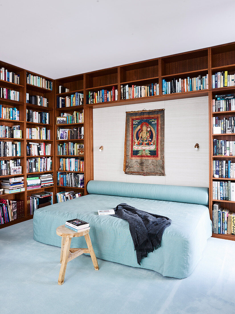 Doppelbett und Nackenrolle mit hellblauem Bezug, umrahmt vom Bücherregal im Schlafzimmer