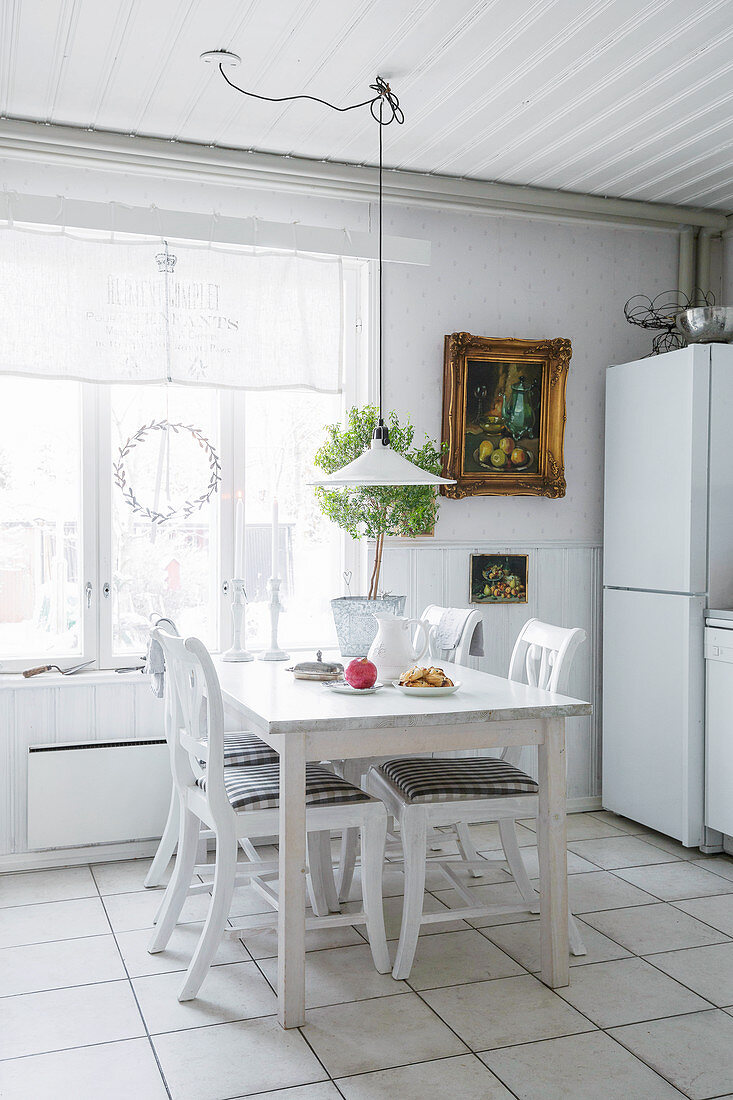 Holztisch mit Stühlen vor Fenster in weißer Küche