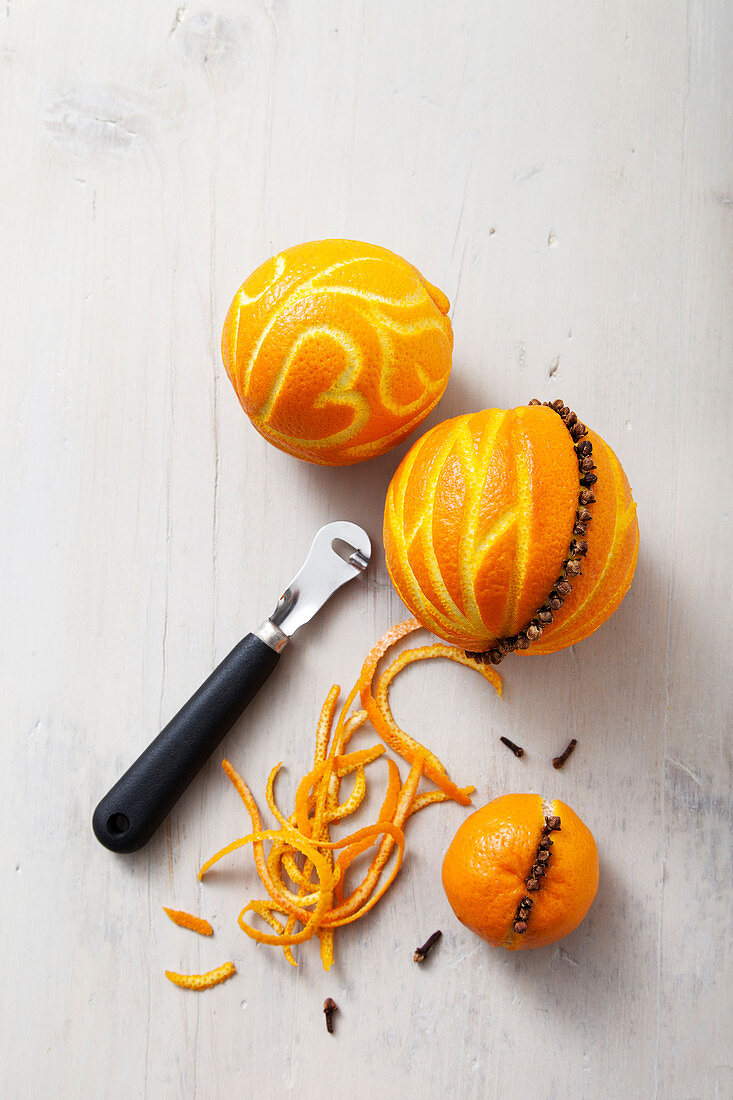 Orangen mit dem Zestenreißer und Nelken dekorieren