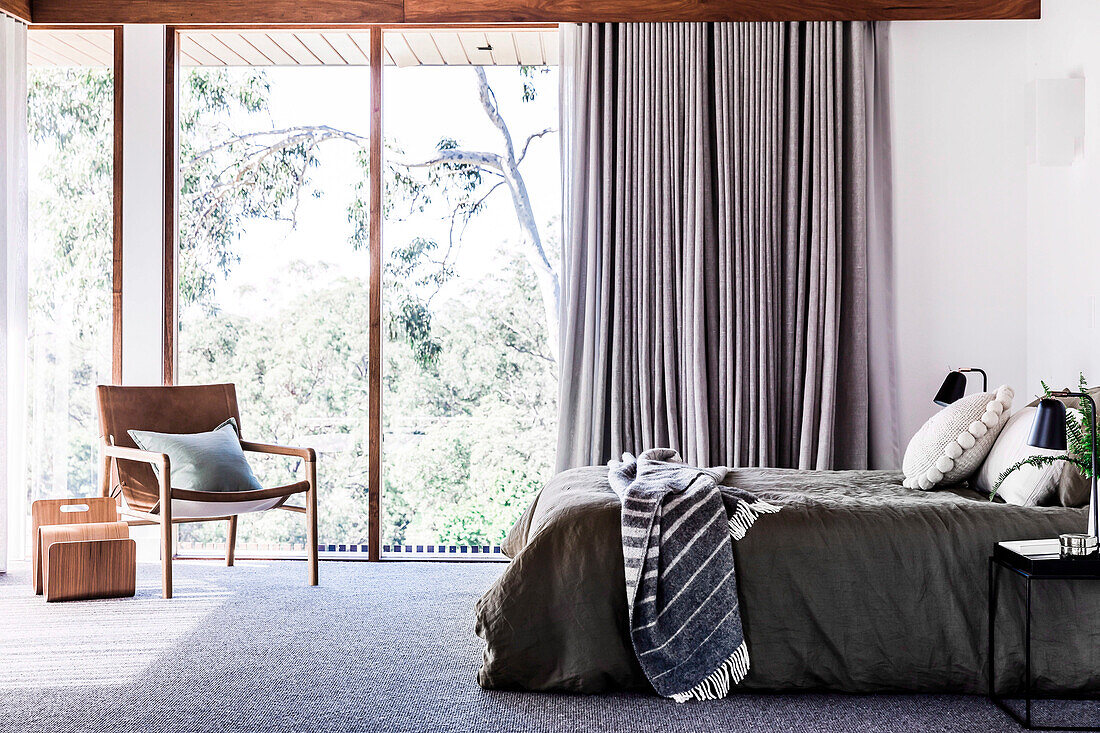 Double bed and armchair in the bedroom with floor-to-ceiling windows