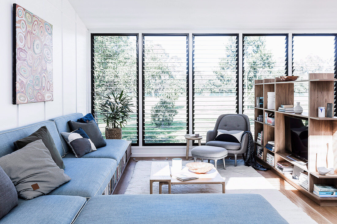 L-förmige Couch mit Stauraum und Regal als Raumteiler in hellem Wohnbereich