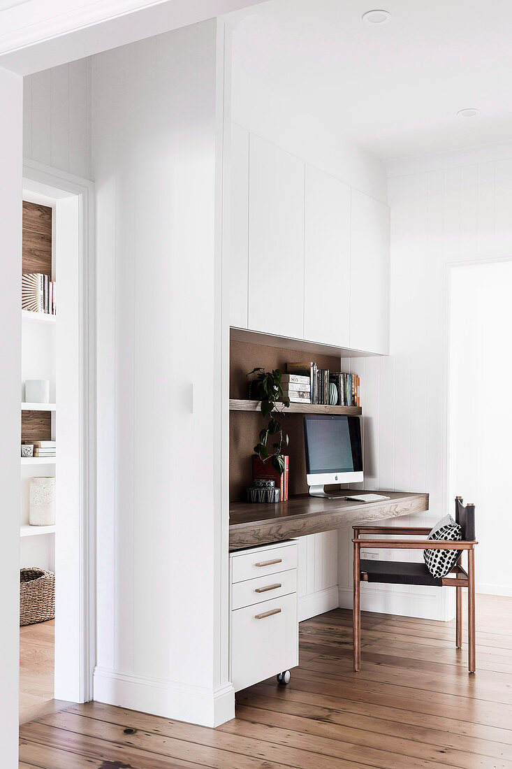 Weißer Einbauschrank und integrierte Holzplatte als Schreibtisch im Arbeitszimmer