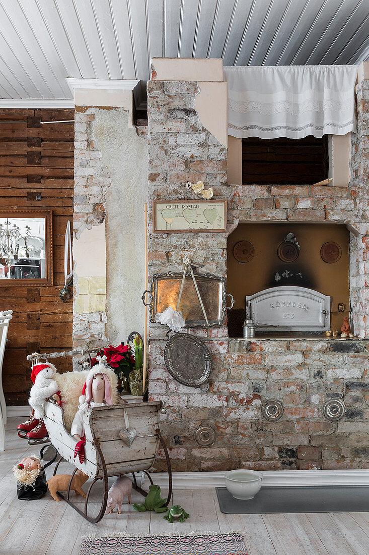 Christmas decorations on vintage sledge next to rustic brick fireplace