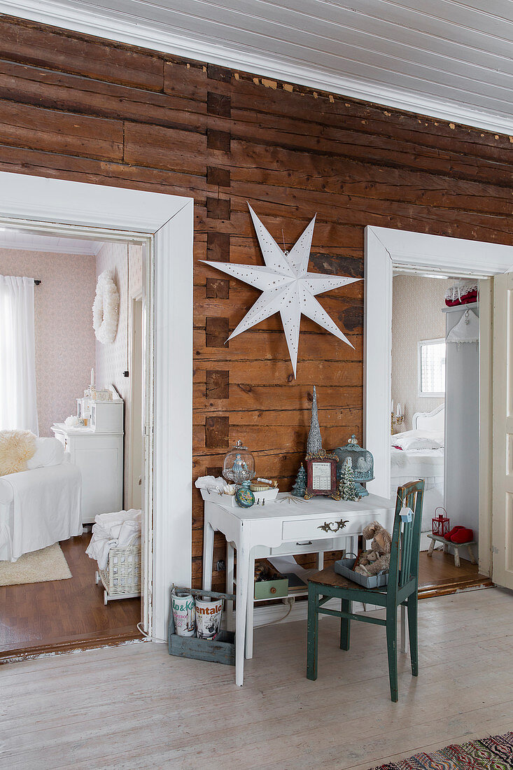 Table with drawer and chair below white star on wooden wall flanked by white door frames