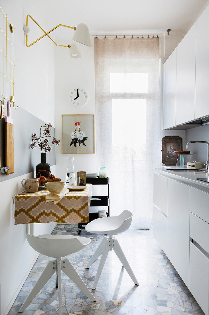 Schmale Küche mit weißer Küchenzeile, Wandtisch und Barhockern