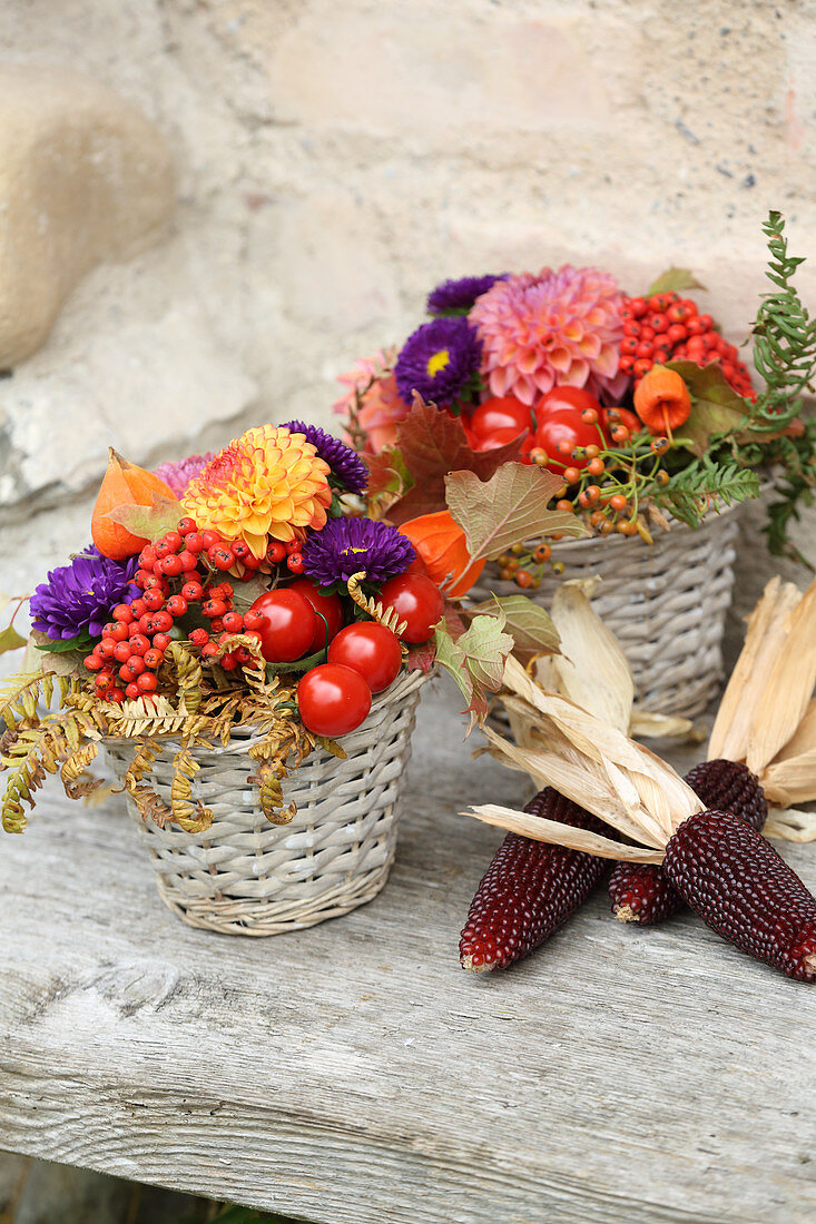 Rustikale Herbstdeko mit Blumengestecken und Maiskolben