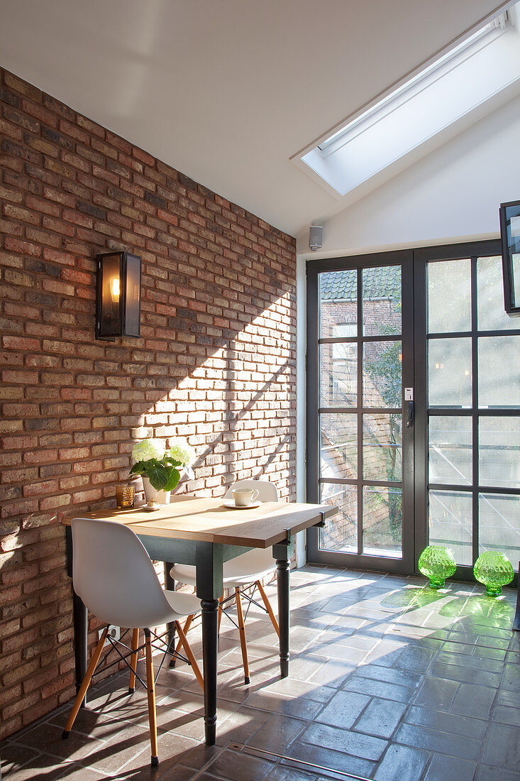 Dining table against brick wall and in front of glass door
