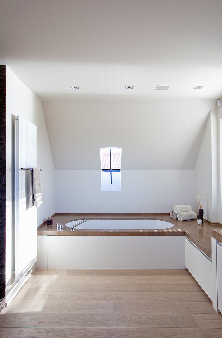 Eingebaute Badewanne mit Natursteinrand und Ablage in minimalistischem Badezimmer