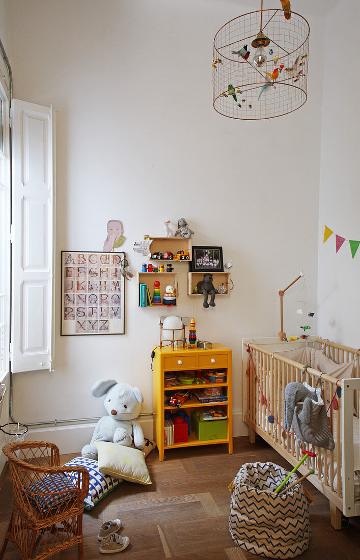 Schlichtes Kinderzimmer mit Gitterbett und Holzboden