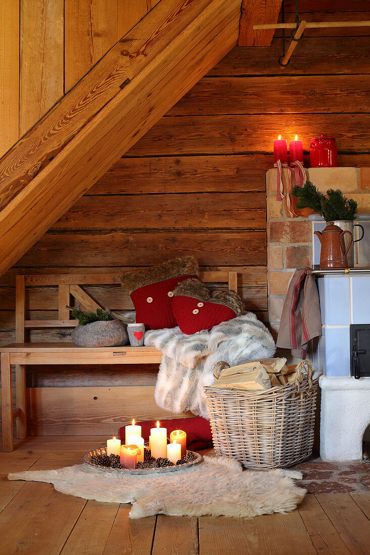 Arrangement of candles and bench next to wood-burning stove in rustic wooden hut