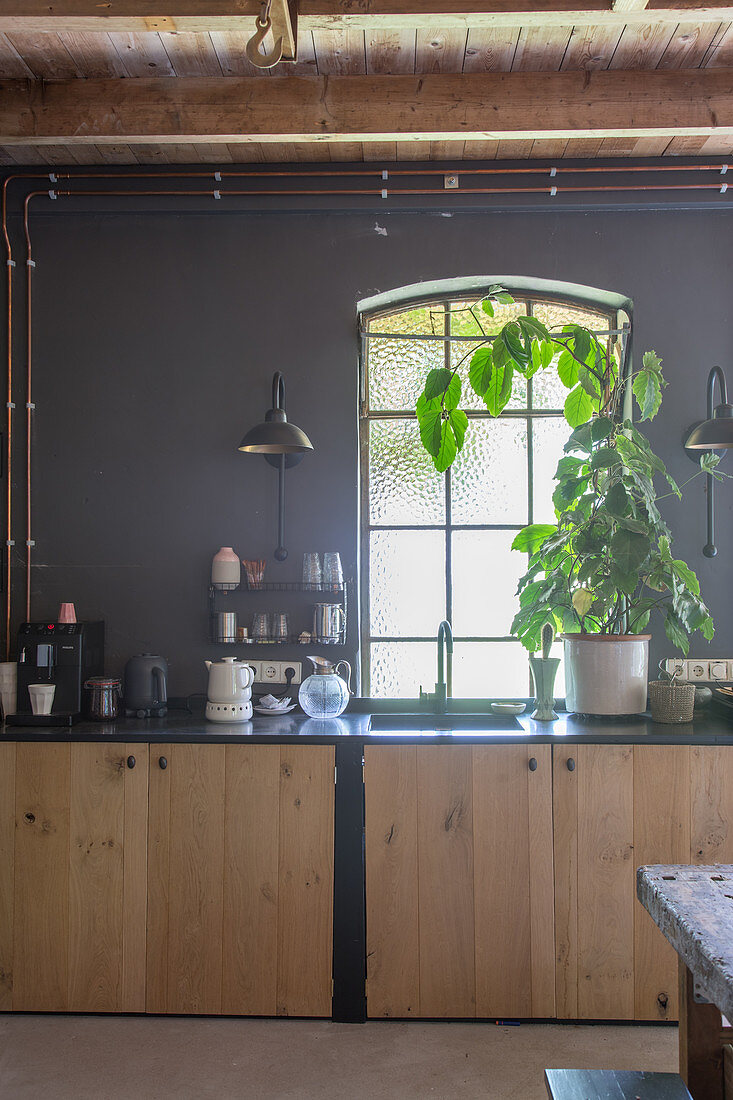 Unterschränke mit Holzfront vor Fenster in Küche mit dunkelgrauer Wand