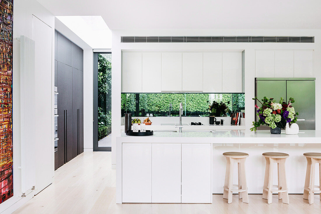 White, open kitchen with kitchen counter and bar stools