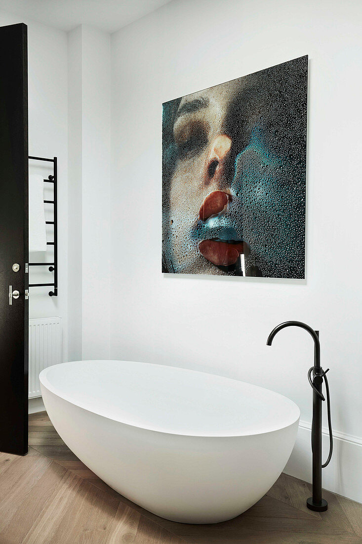 Freestanding bathtub with stand mixer and modern art on the wall in the bathroom