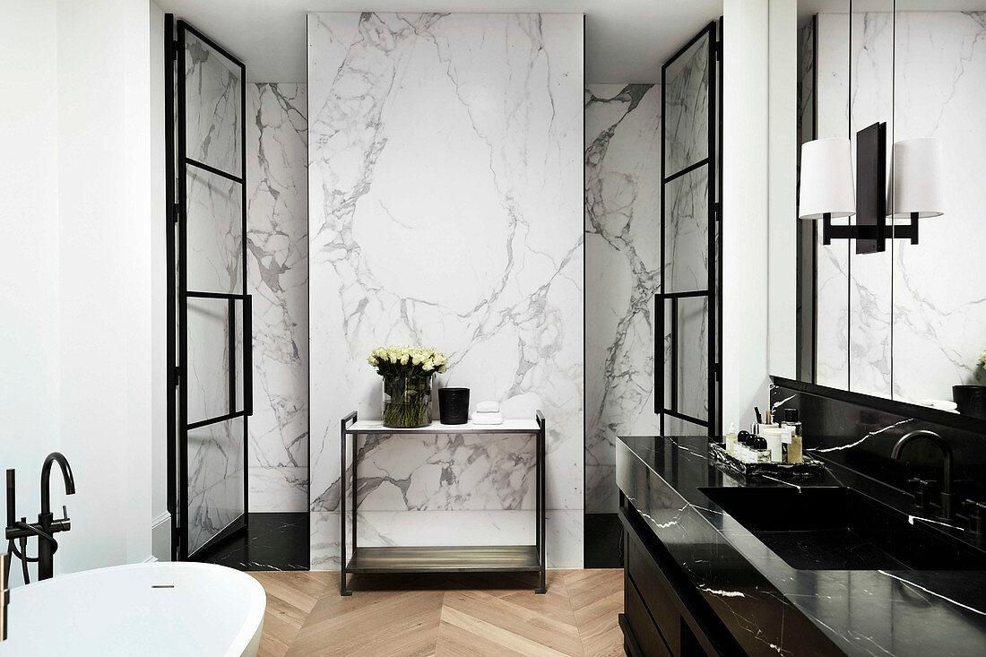 Waschtisch aus schwarzem Marmor in luxuriösem Bad, Wand mit weißer Marmor-Verkleidung