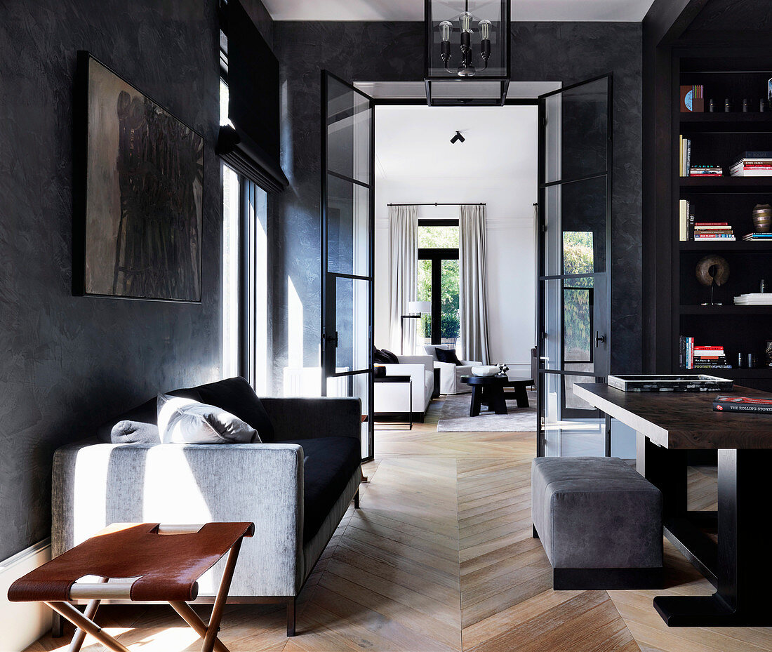 Schreibtisch, Regal und Sofa in elegantem Arbeitszimmer mit dunklen Wänden