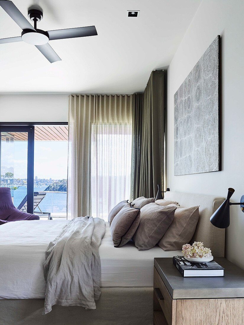 Doppelbett mit Kissensammlung im Schlafzimmer mit Balkon