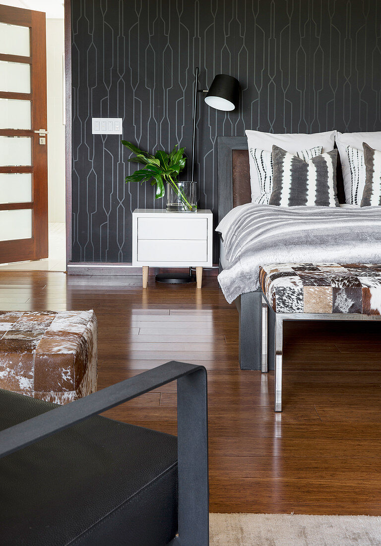 Doppelbett und weißer Nachtkästchen im Schlafzimmer mit schwarzer Tapete