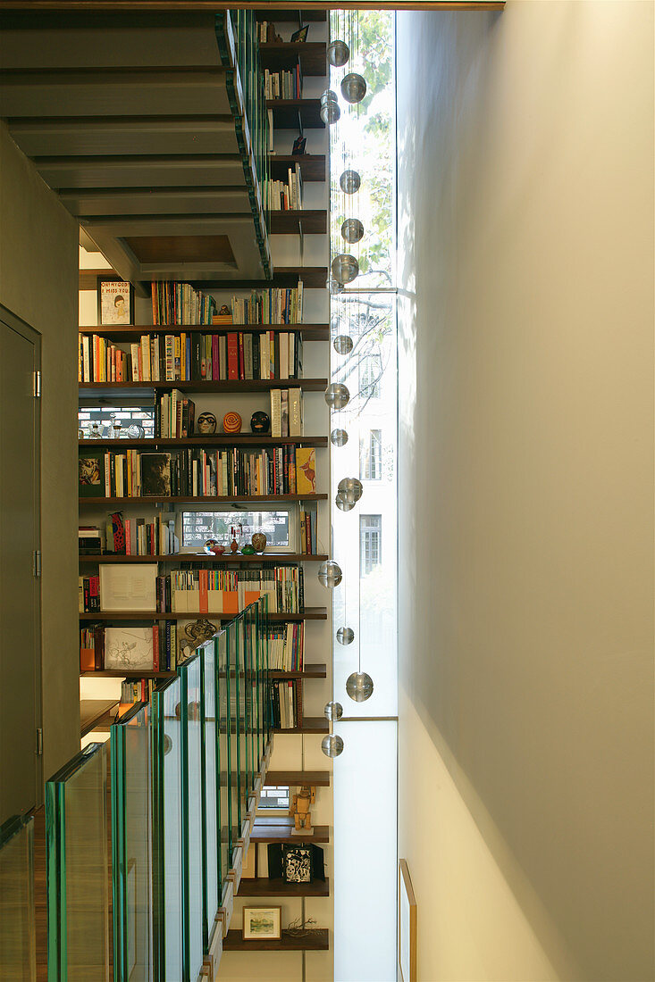 Narrow, vertical strip window and bookcase extending over three storeys