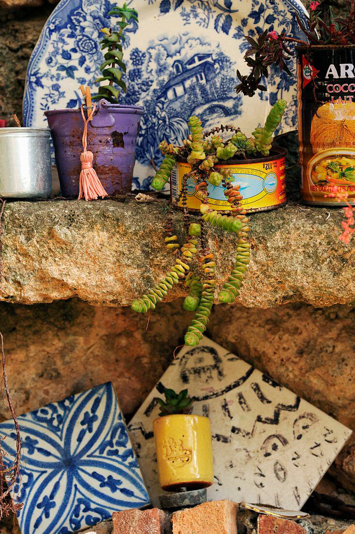 Fliesen, Grünpflanze und Wandteller auf Natursteinablage