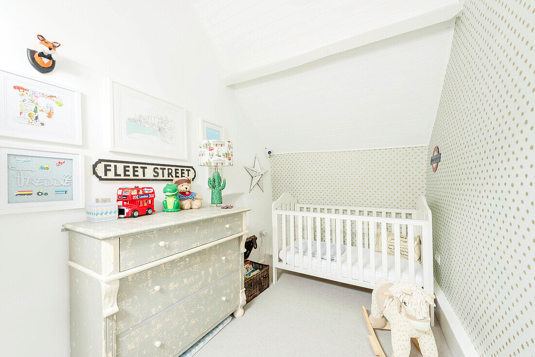 Cot in small nursery decorated in pale grey and white