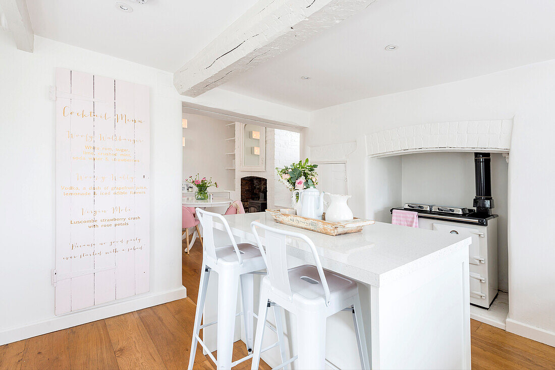 Breakfast bar in white kitchen with old stove and ceiling beams