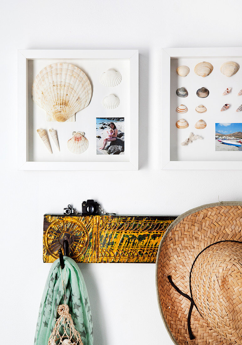 Sea shells and holiday photos in deep frames above coat pegs
