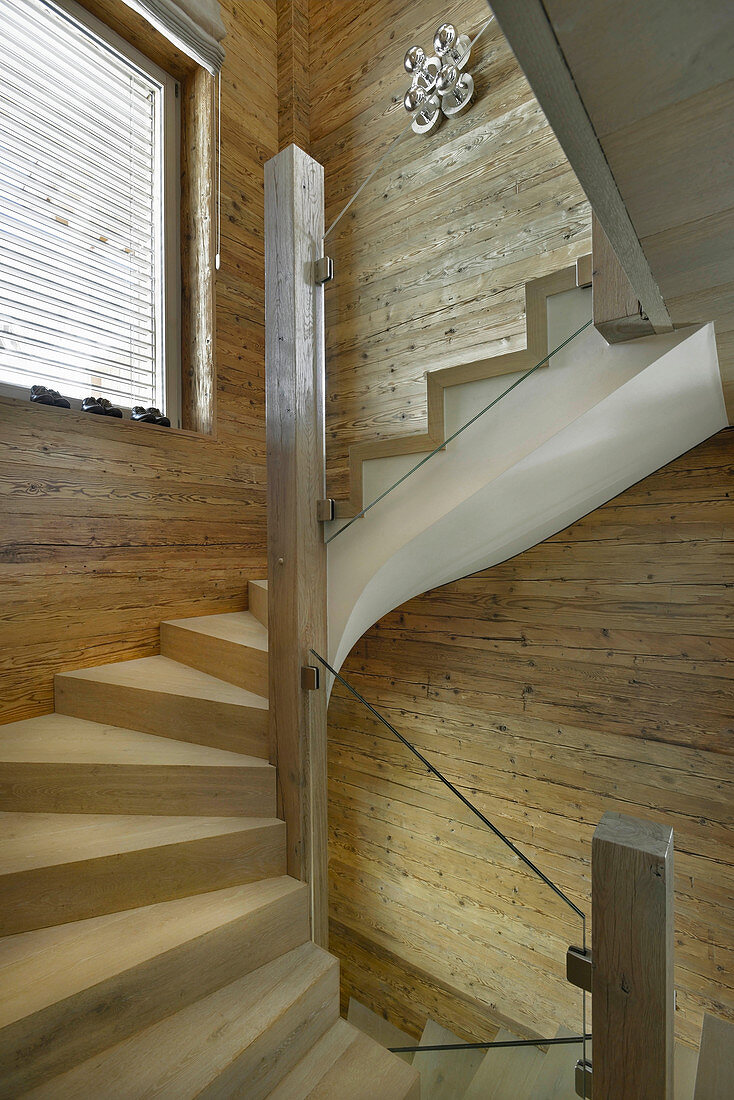 Treppe mit Glasbalustrade im Chalet mit holzverkleideten Wänden