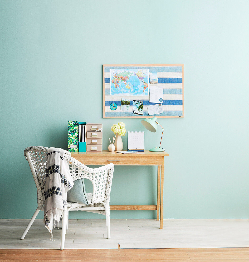 Desk in front of light blue wall with blue pin board