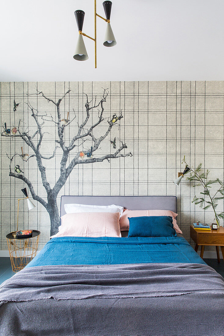 Double bed against wallpaper with tree motiv