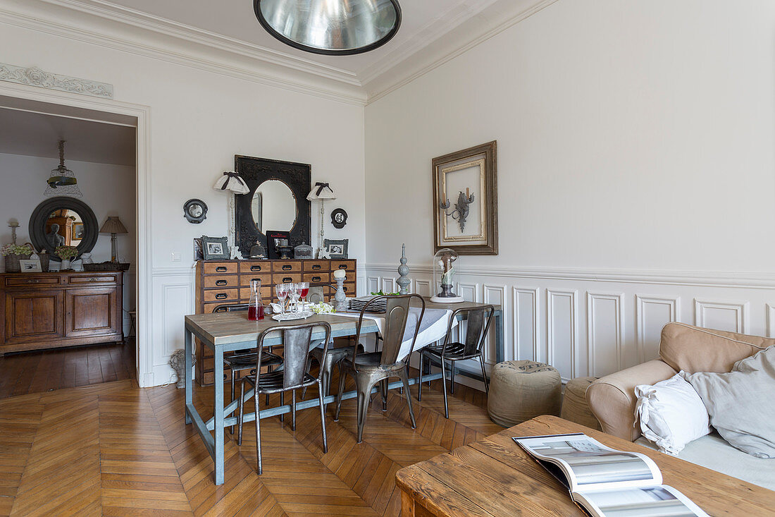 Rustic dining table, metal chairs and chest of drawers with wooden table and pale couch in foreground