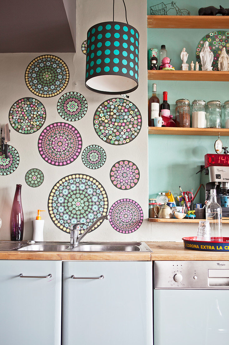 Circular mandalas on wall and shelves on wall in green niche above kitchen counter
