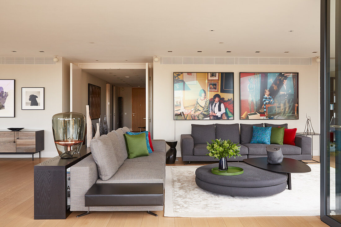 Elegante Lounge mit grauer Polstergarnitur, Designer-Couchtisch und großformatigen Fotos an der Wand