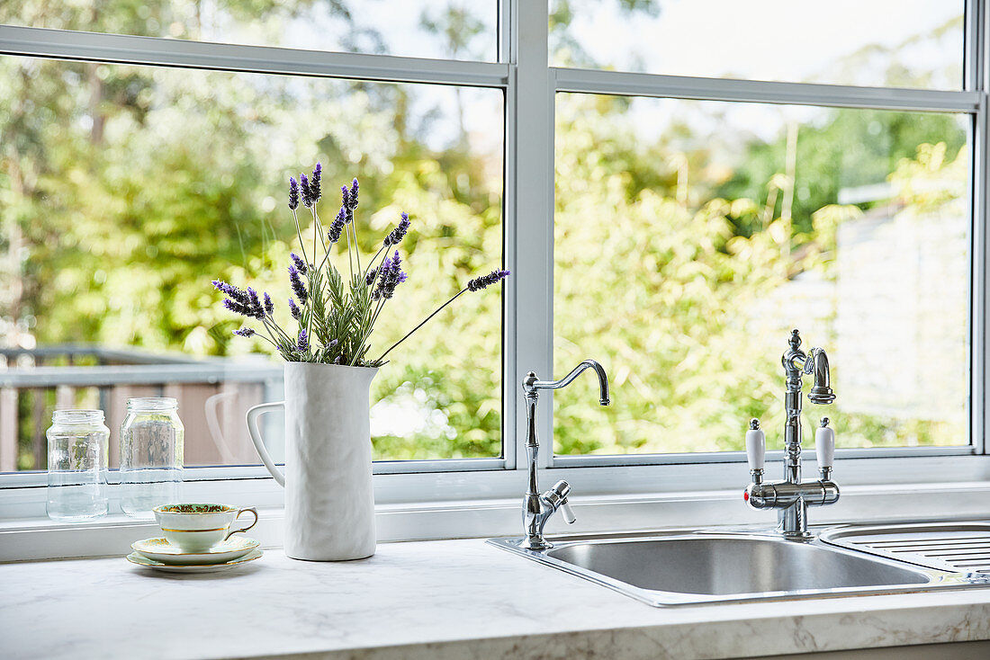 Küchenarbeitsplatte mit intergriertem Spülbecken vor Fenster, Krugvase mit Lavendelblüten