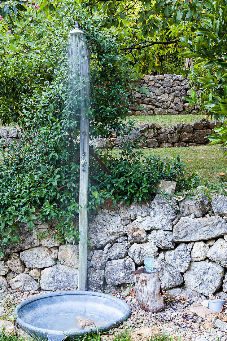 Outdoor shower against stone wall in garden