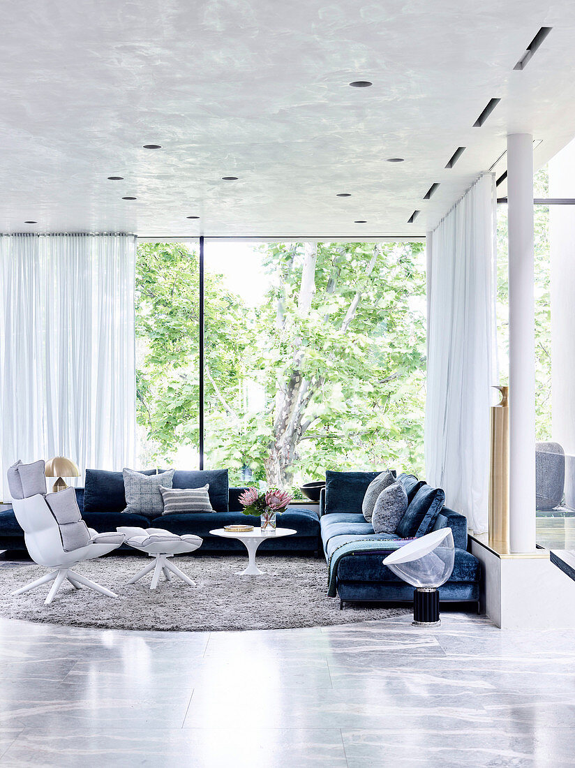 Elegante Lounge mit Polstergarnitur und Designersessel vor Fensterfront