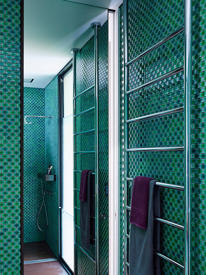 Handtuchtrockner und Spiegelwand in der Dusche mit Mosaikfliesen in Grüntönen