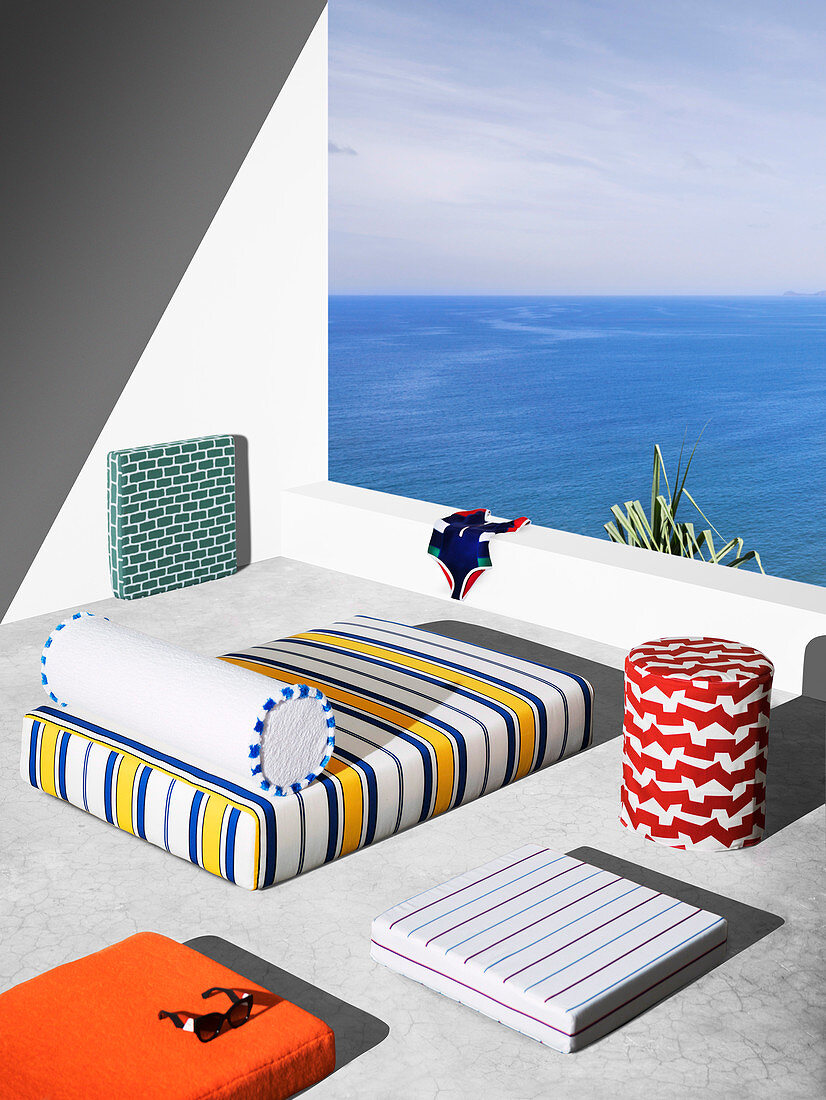 Mattress, seat cushion and bolster with colorful covers on terrace with sea view