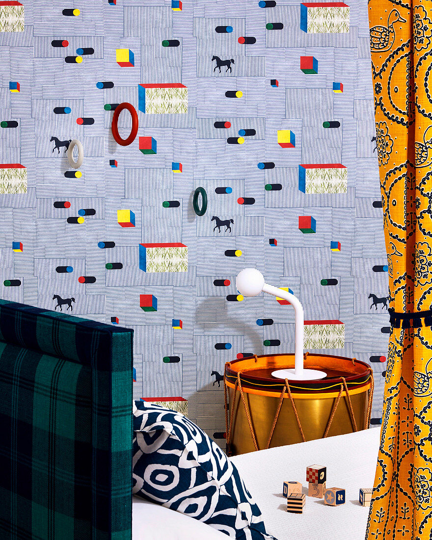 Designer wallpaper with gymnastic rings, drum as a bedside table next to bed in the children's room