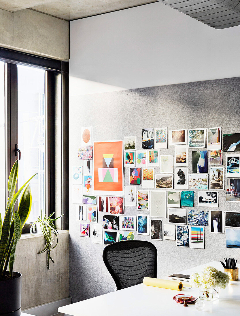 Postkartensammlung an Pinnwand, weißer Schreibtisch mit schwarzem Stuhl im Arbeitszimmer