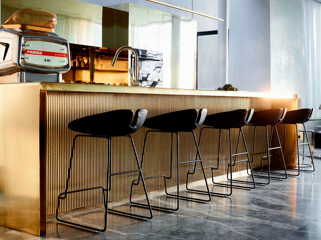 Kücheninsel aus poliertem Messing mit Barhockern in elegantem, offenem Wohnraum mit Marmorfliesen