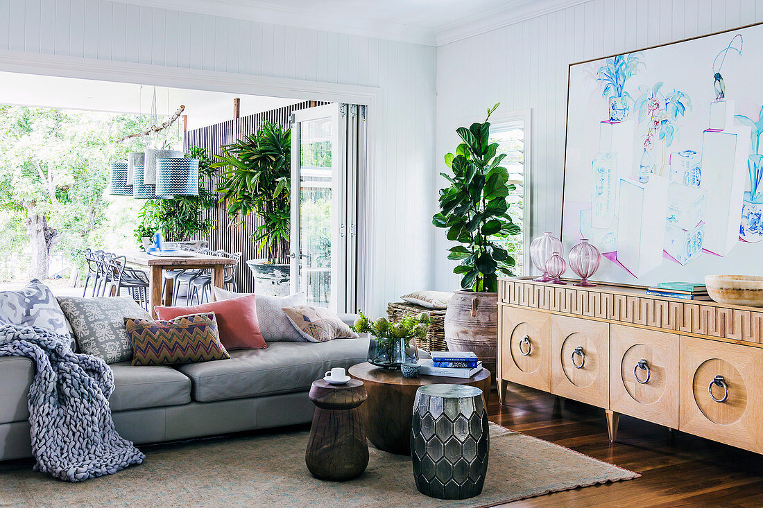 Sideboard, Zimmerpflanze, Couchtisch und Sofa vor geöffneter Terrassentür im Wohnzimmer